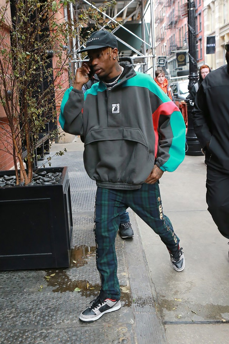 Travis Scott pairs an anorak jacket with tailored plaid trousers and the Supreme x Nike SB Dunk Low.